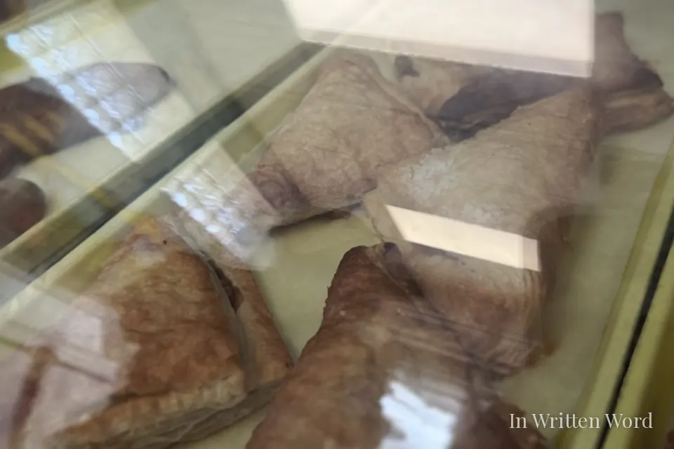 Pastries displayed behind glass at Piman Bouk Bakery in Little Haiti, Miami, including triangular puff pastries arranged on trays.
