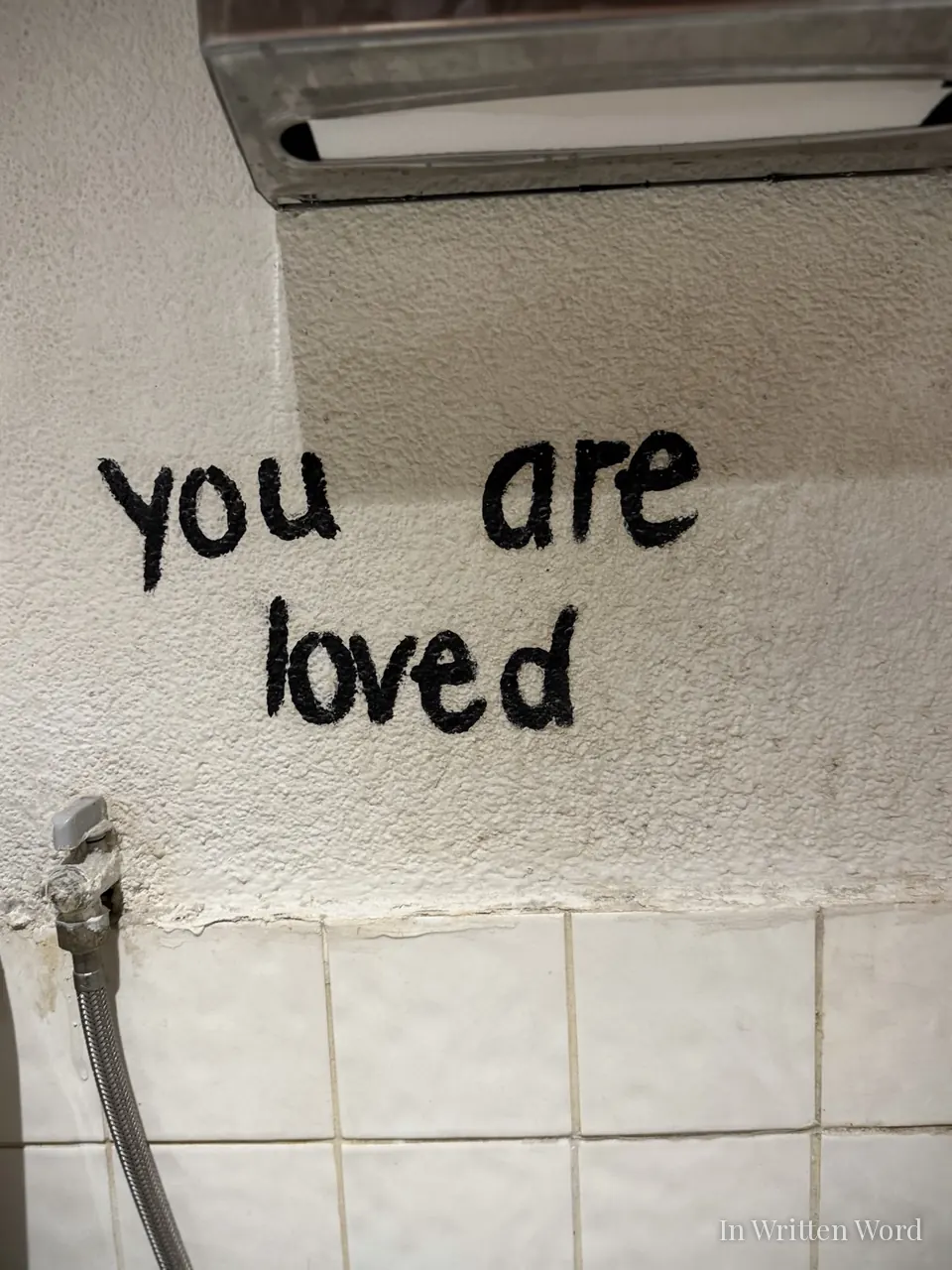 The words “you are loved” written in simple black paint on a white tiled wall inside Espresso Lab in Bebek, Istanbul